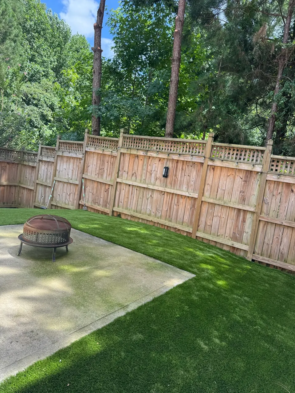 After: Clean backyard with astroturf, fire pit and fence visible